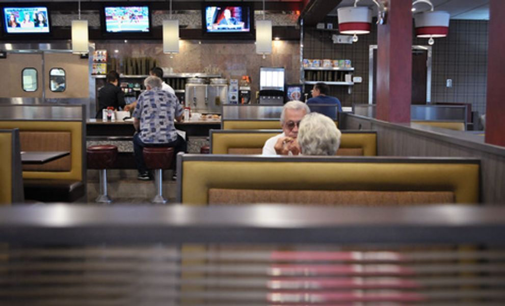 A couple of people are sitting in a booth in a restaurant