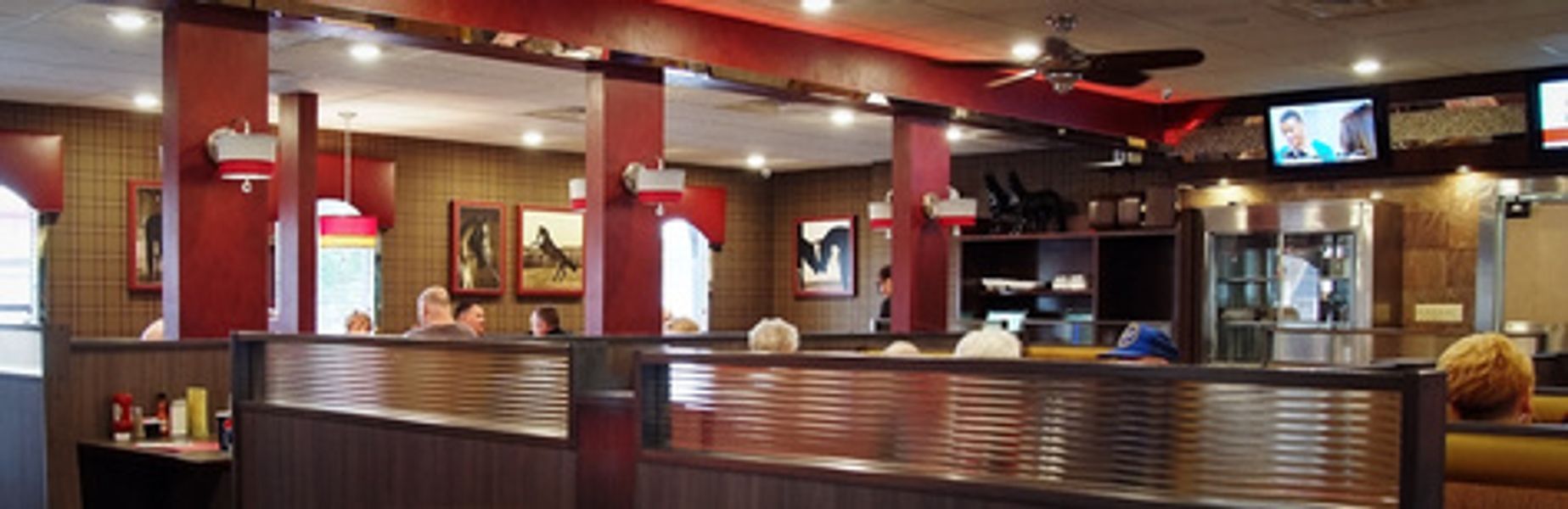 A restaurant with a ceiling fan and a television on the wall