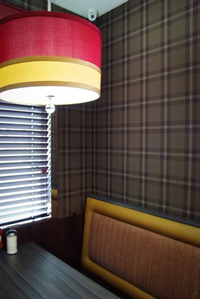 A restaurant booth with a red and yellow lamp hanging from the ceiling