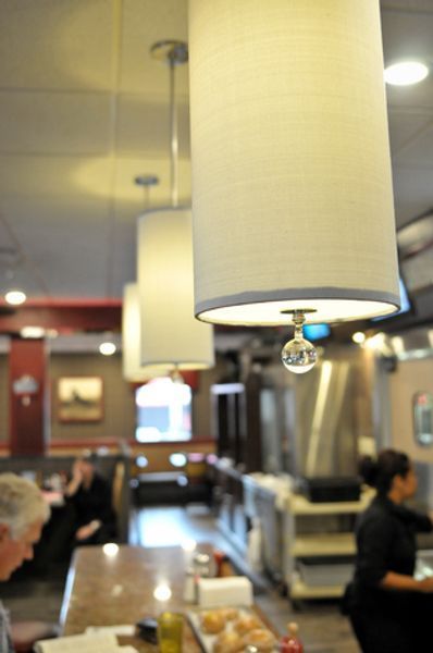 A restaurant with people sitting at tables and a lamp hanging from the ceiling