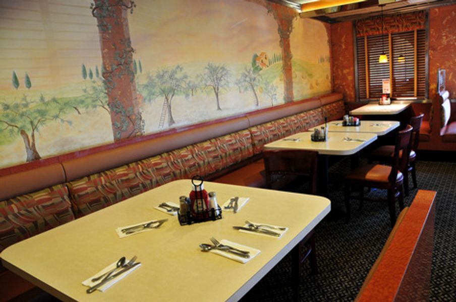 A restaurant with tables and chairs and a mural on the wall