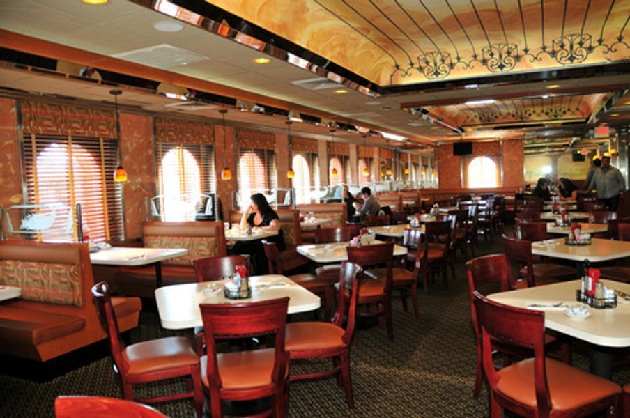 A restaurant with tables and chairs and people sitting at them