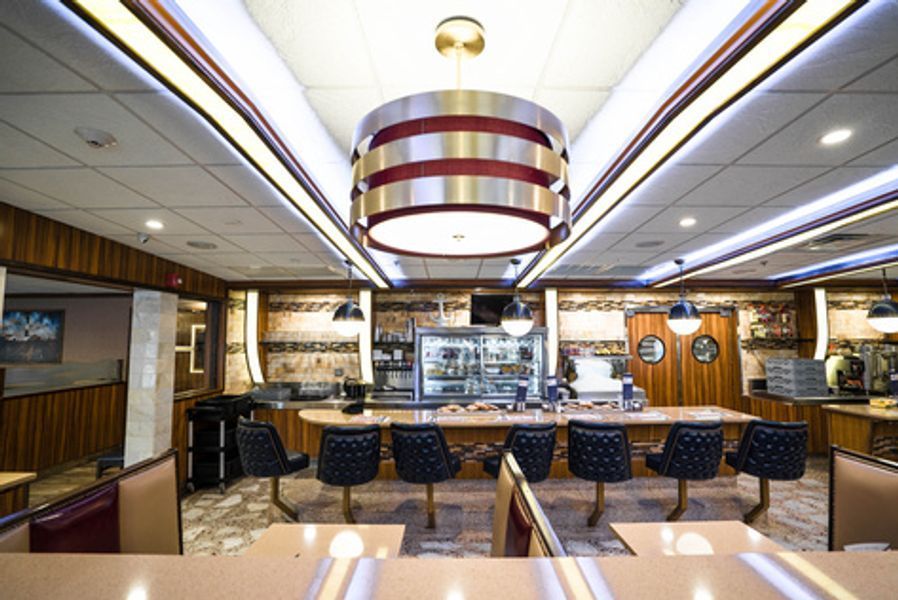 A diner with tables and chairs and a large light hanging from the ceiling