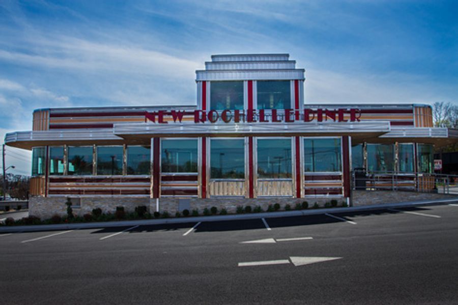 A diner with a lot of windows is sitting on the side of the road