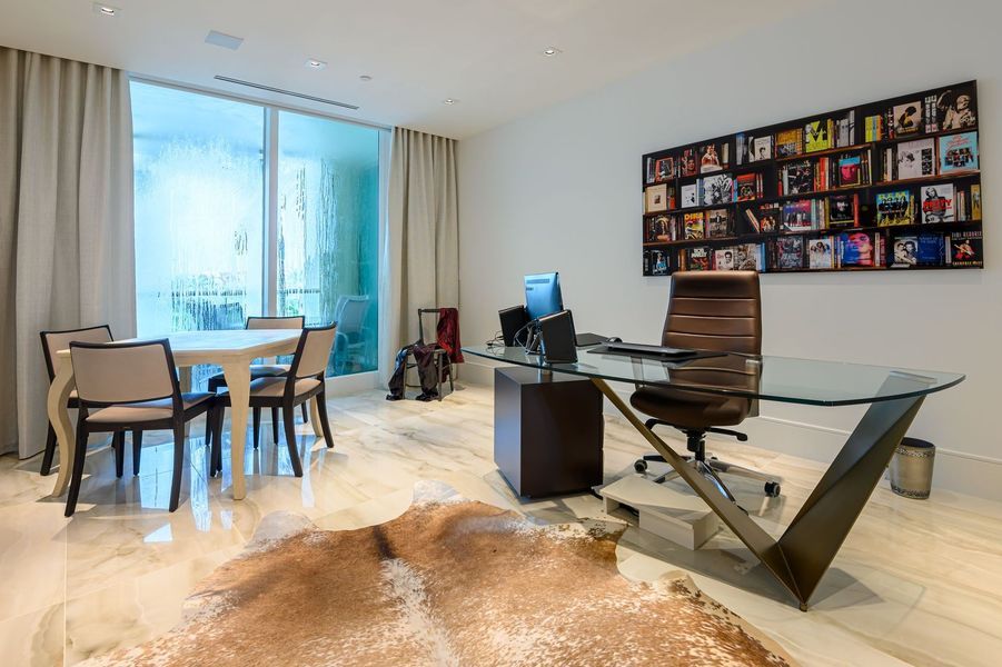 A room with a desk, chairs, a table and a rug