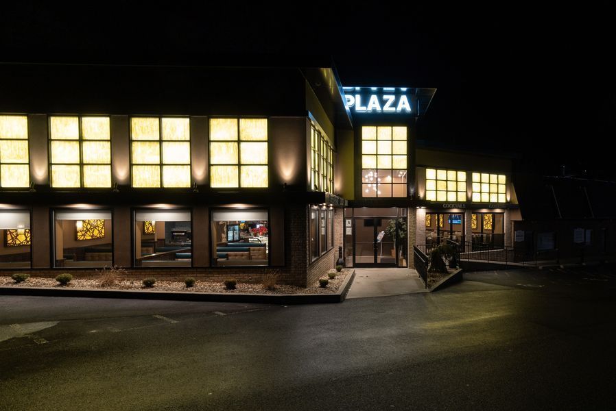 A large building with a sign that says plaza is lit up at night