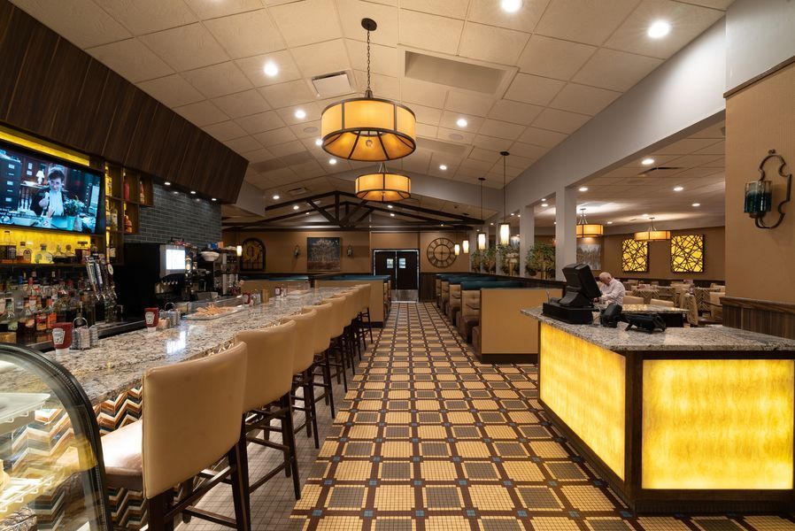 The interior of a restaurant with a long bar and chairs