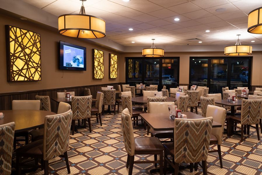 A large dining room with tables and chairs and a television on the wall