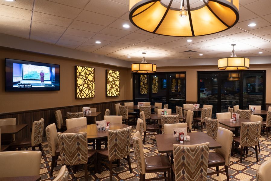 A large dining room with tables and chairs and a flat screen tv on the wall