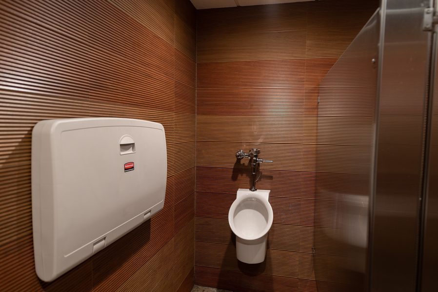 A bathroom with a urinal and a changing table