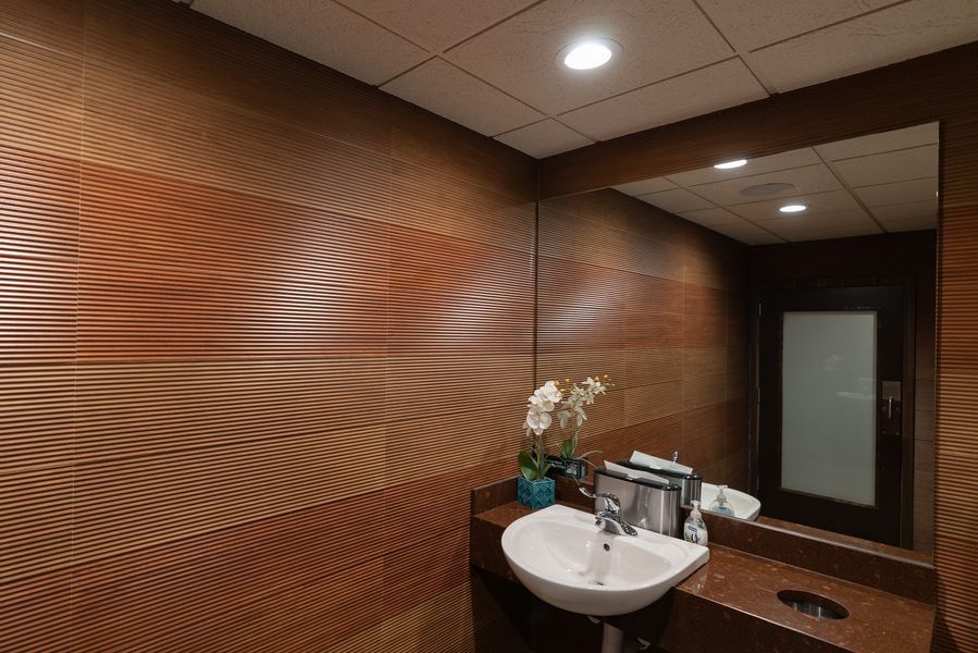 A bathroom with a sink, mirror and wooden wall