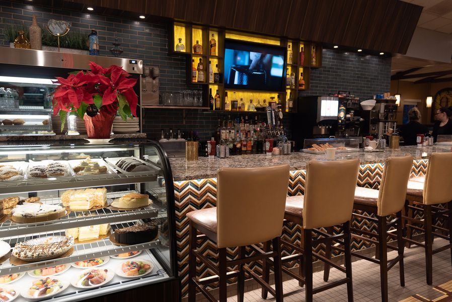 A restaurant with a bar and a display case of desserts