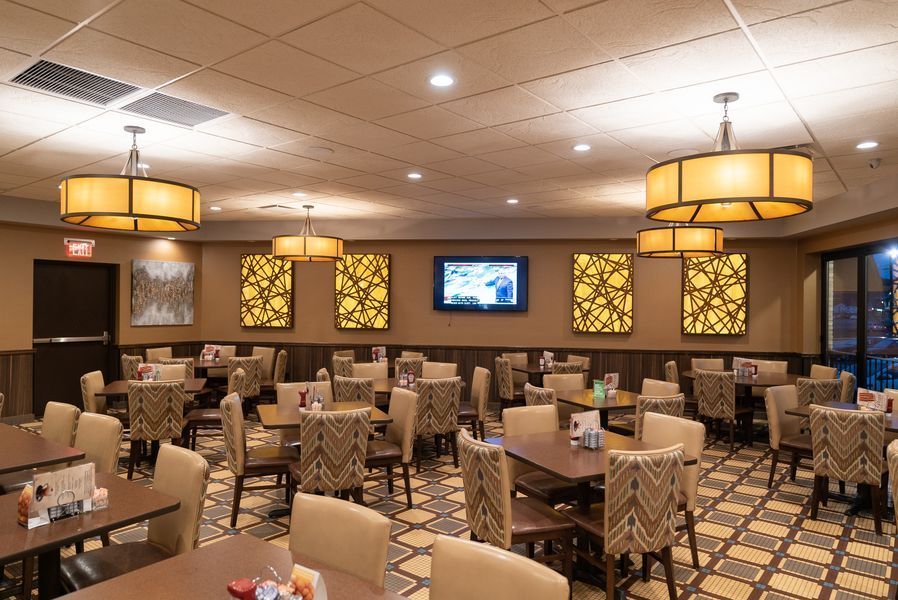 A large dining room with tables and chairs and a television on the wall