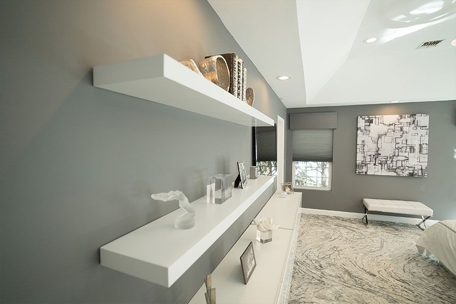 A living room with gray walls and white shelves