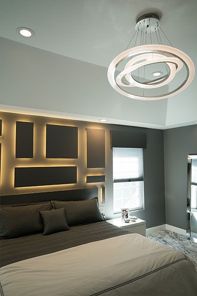 A bedroom with a large bed and a chandelier hanging from the ceiling