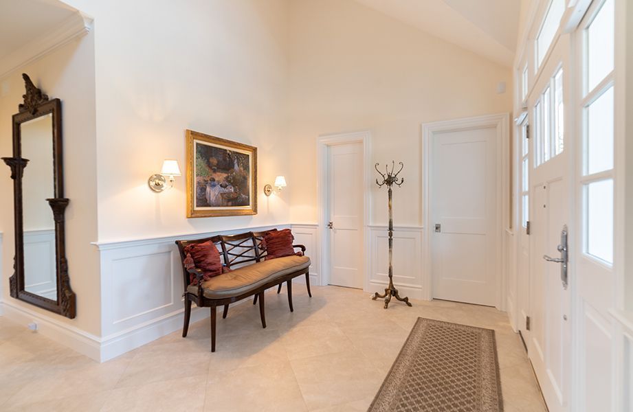 A hallway with a bench, mirror, and painting on the wall