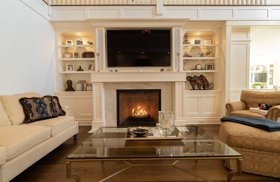 A living room with a fireplace, couch, chair and television