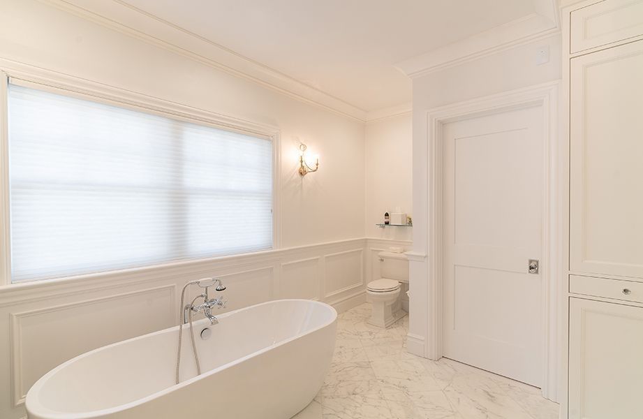 A bathroom with a tub, toilet, sink and window