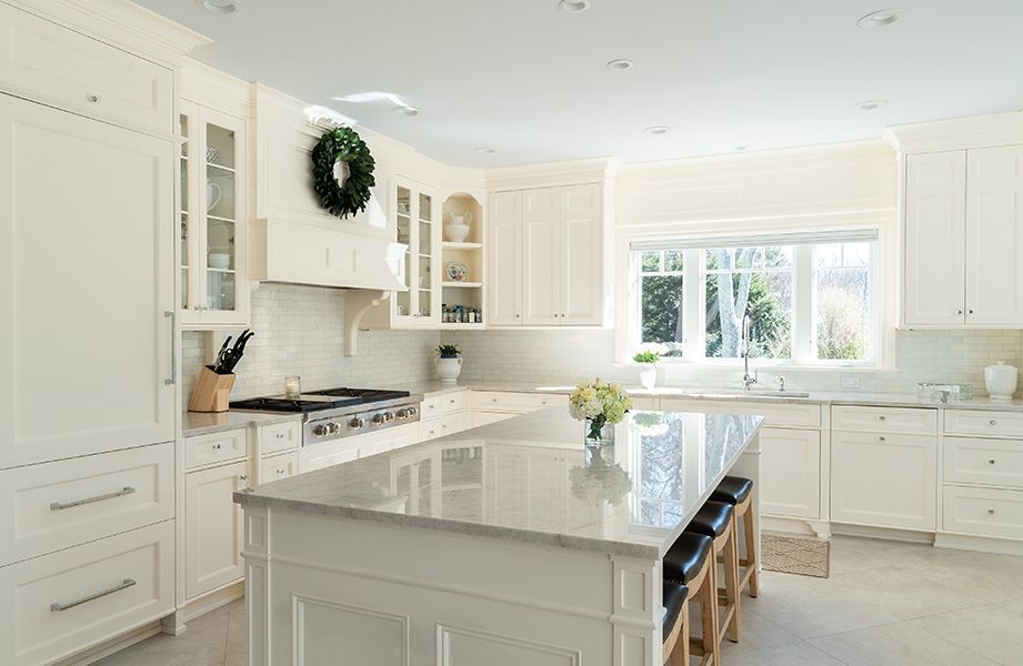 A kitchen with white cabinets, granite counter tops, and a large island