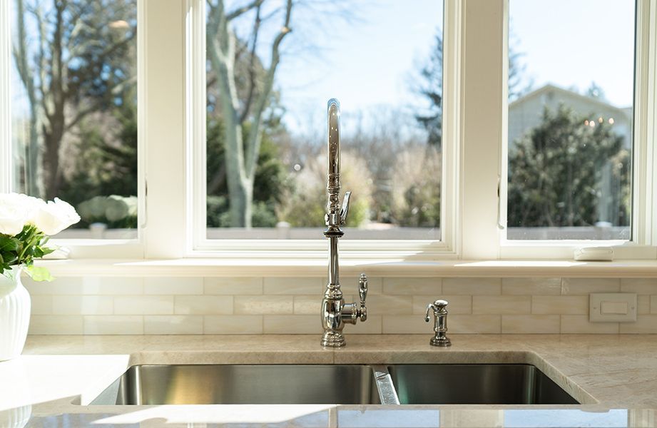 A kitchen sink with a faucet and a window in the background