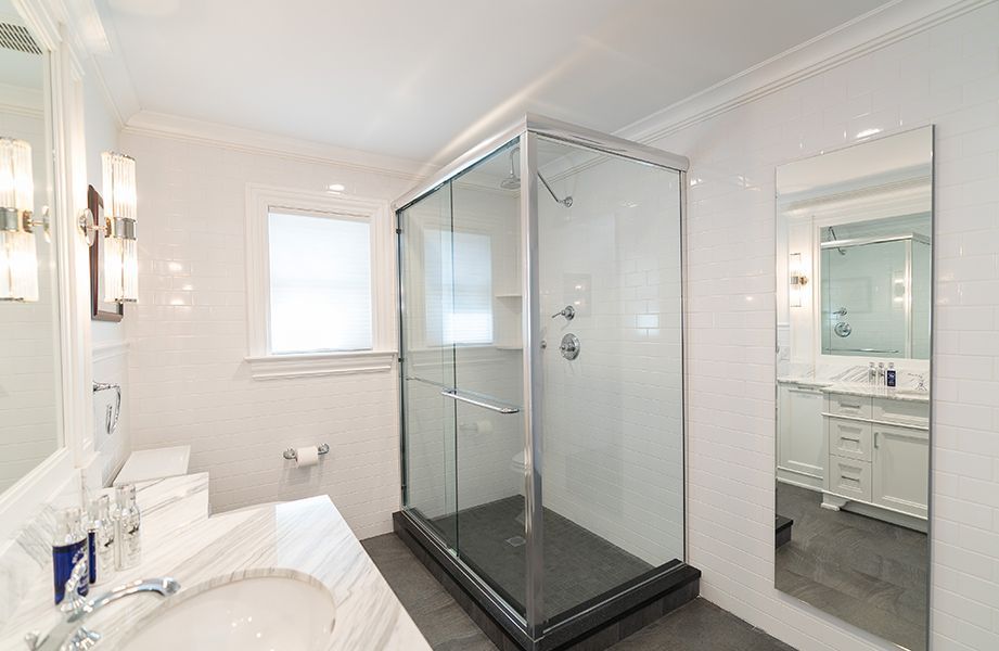 A bathroom with a walk in shower, sink and mirror