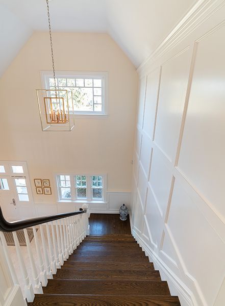 A wooden staircase with a white railing and a chandelier hanging from the ceiling