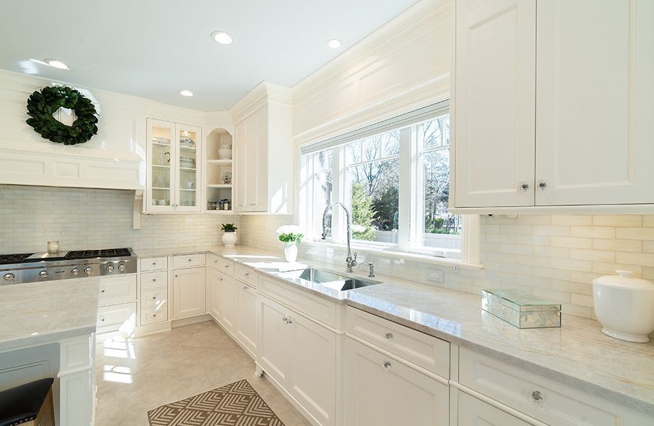 A kitchen with white cabinets, granite counter tops, a sink and a stove