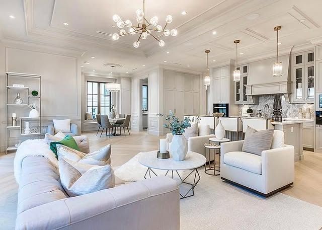 A living room with a couch , chair , table and chandelier.