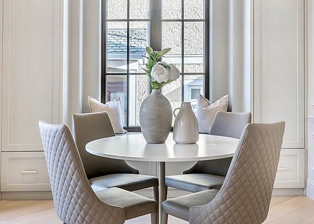 A dining room table with four chairs and a vase of flowers on it.