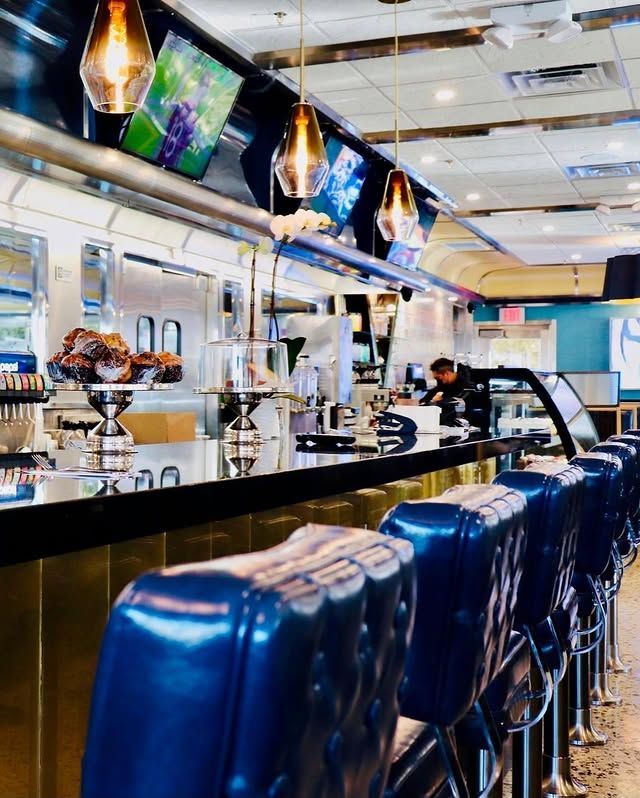 A diner with a long counter and blue chairs