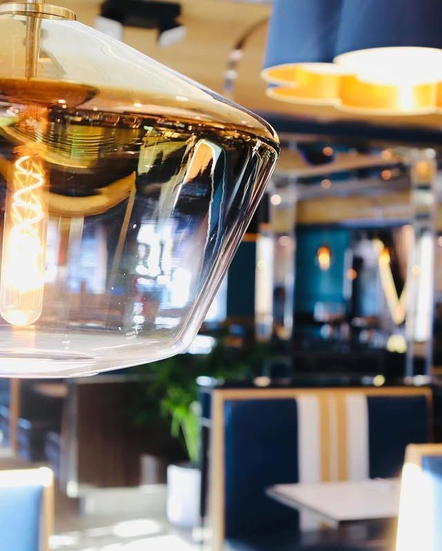 A glass pendant light is hanging from the ceiling in a restaurant.