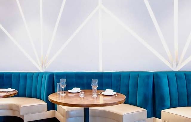 A restaurant with a blue booth and a table with glasses on it.