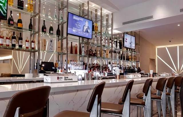 A bar with a lot of bottles of alcohol and a television on the wall.