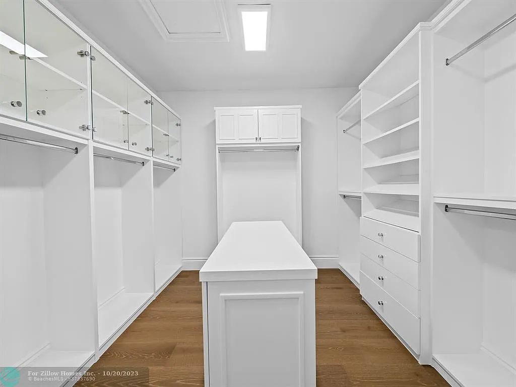 A walk in closet with lots of white cabinets and shelves.