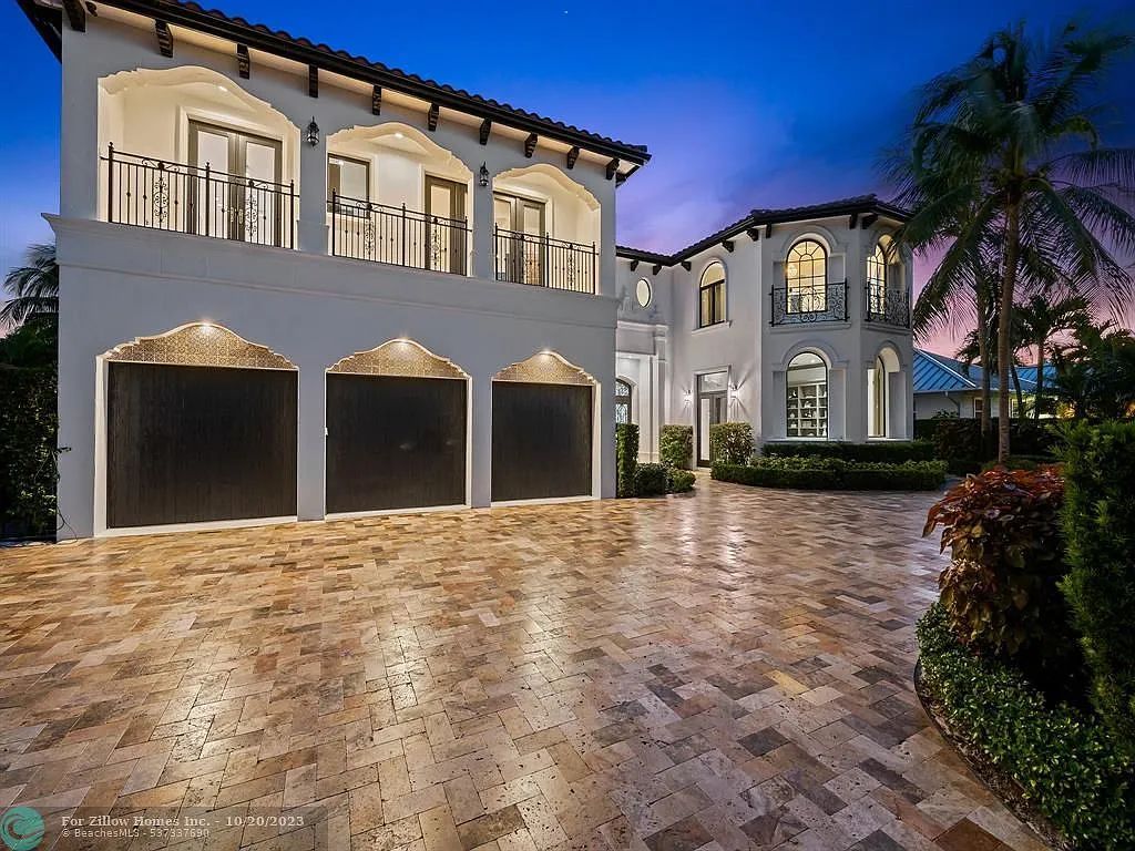 A large white house with a brick driveway in front of it.