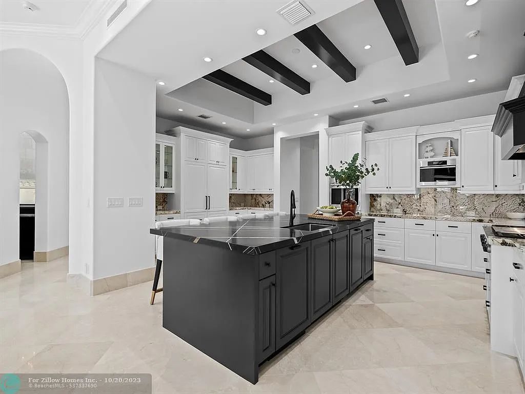 A kitchen with black cabinets and a large island in the middle.