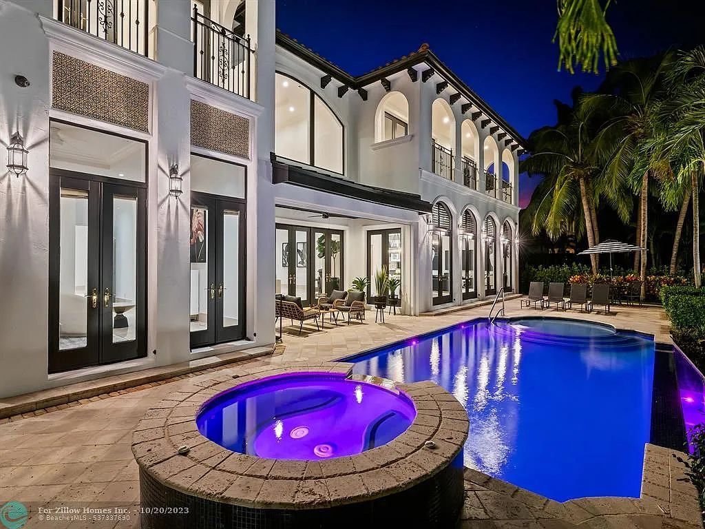A large house with a swimming pool and a hot tub in front of it.