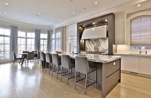 A large kitchen with a large island and a dining room in the background.