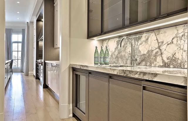A kitchen with a marble counter top , a sink , and a refrigerator.