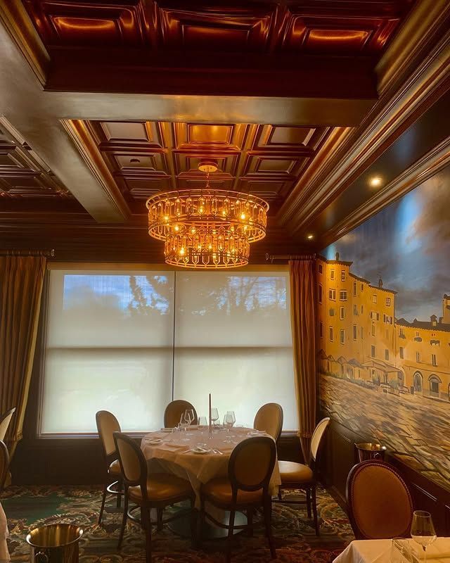 A dining room with a table and chairs and a chandelier hanging from the ceiling.