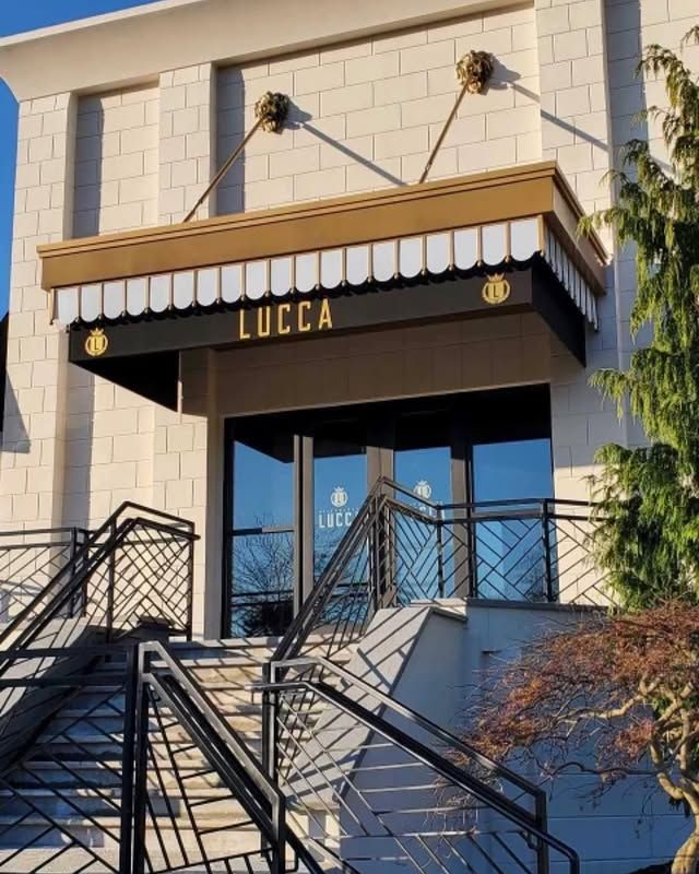A building with stairs and a canopy that says ' lucca ' on it