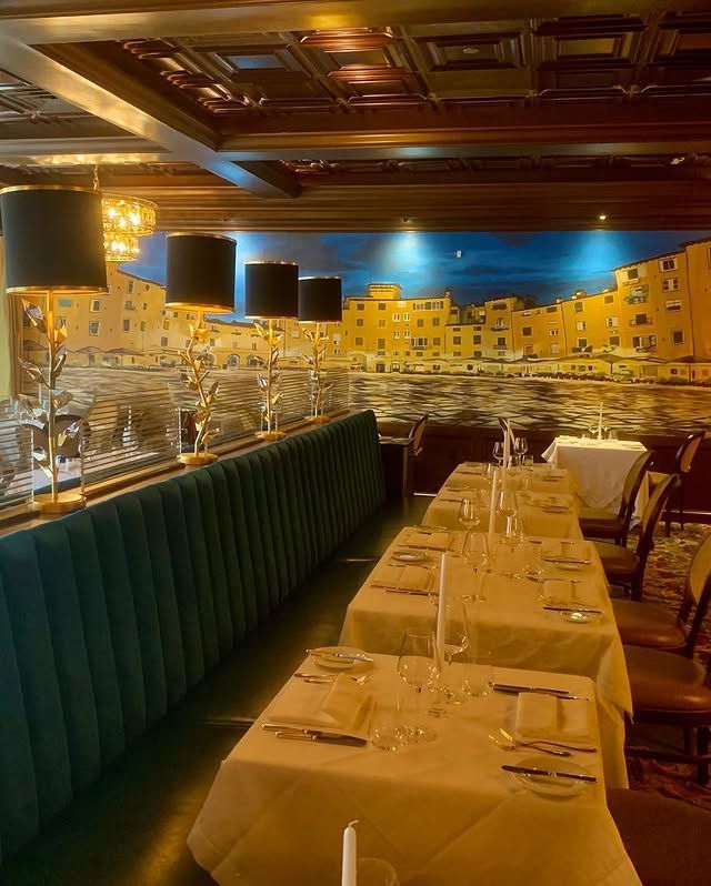 A restaurant with tables and chairs and a painting on the wall.