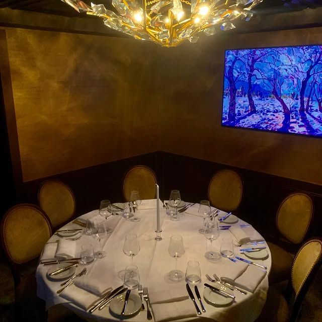 A dining room with a round table and a picture on the wall.