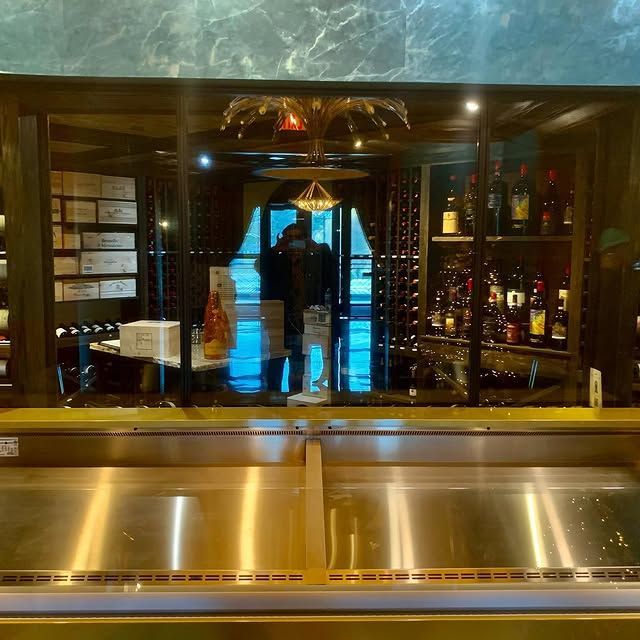 A stainless steel refrigerator in front of a wine cellar