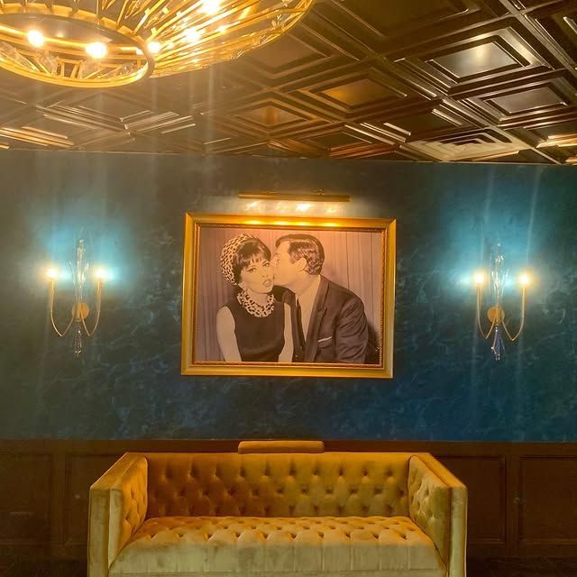 There is a painting of a man and woman kissing on the wall above a couch.