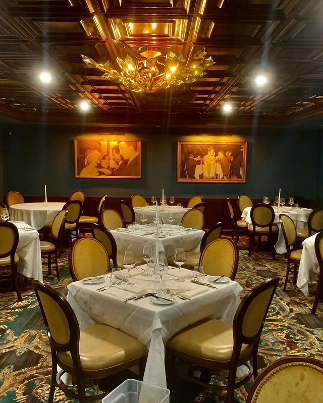 A dining room with tables and chairs and a large chandelier