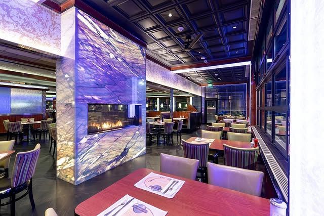 A restaurant with tables and chairs and a fireplace.