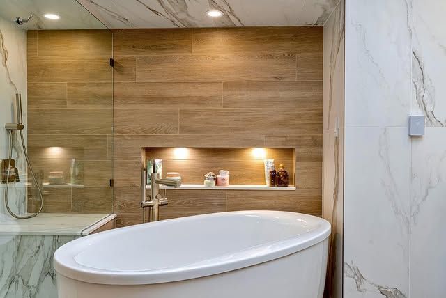 A bathroom with a bathtub , shower , and wooden wall.
