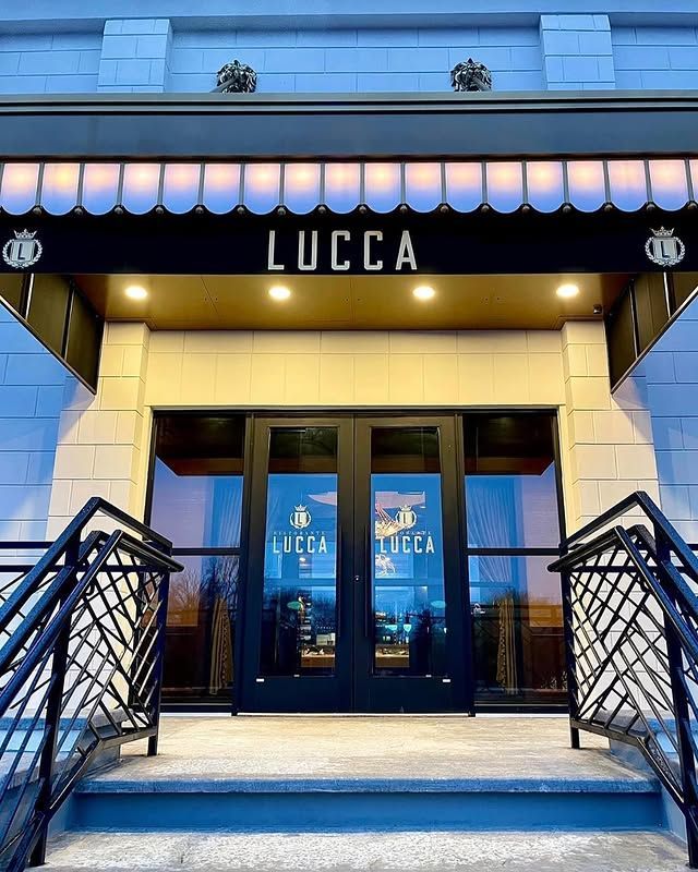 The entrance to a restaurant called lucca with stairs leading up to it.