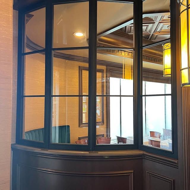 A large window in a room with tables and chairs behind it.